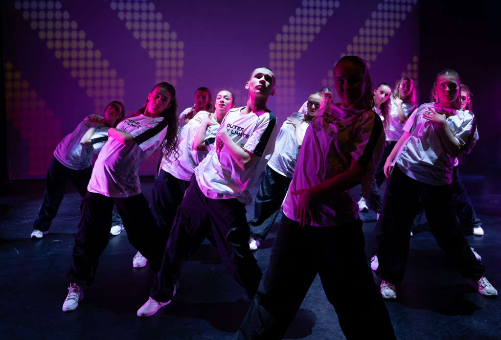 Dancers in  sports clothing all leaning to one side in unison for a Street Dance routine