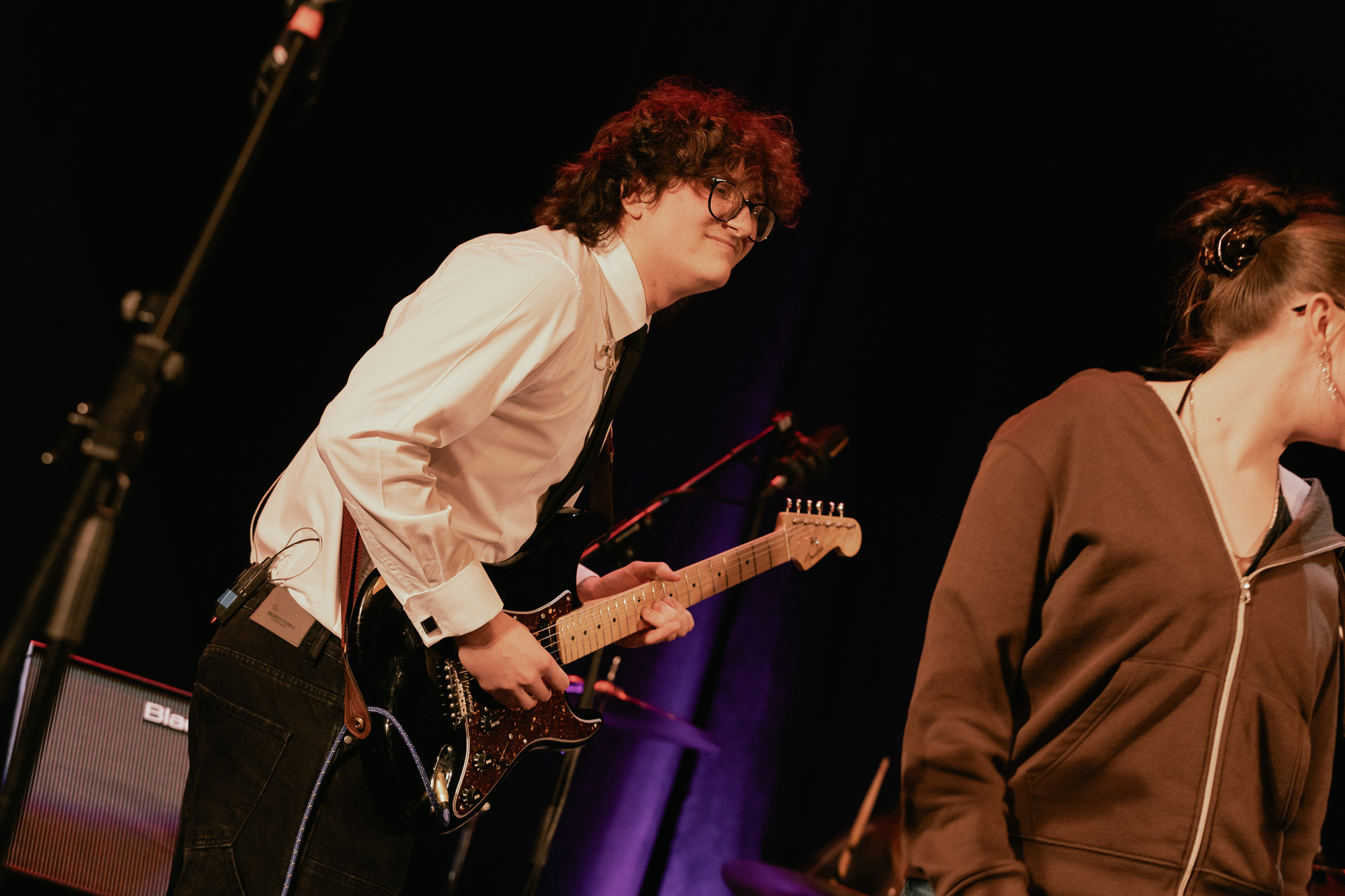 A student playing the electric guitar smiling. 