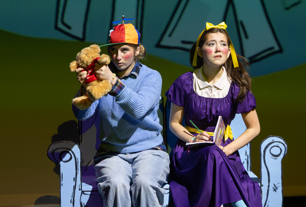 Two students sat down, in children's costumes, one holding a teddy bear.